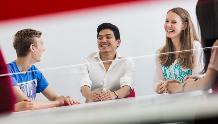Group of students sat at a table, smiling and laughing