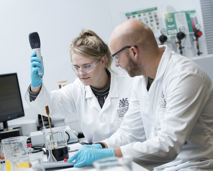 A female student working alongside an academic in a laboratory