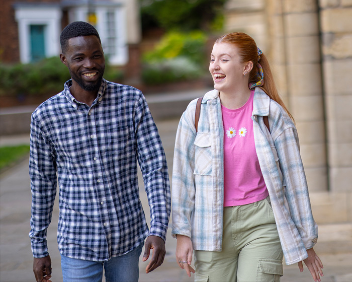 Two students walking and talking next to Lincoln Cathedral