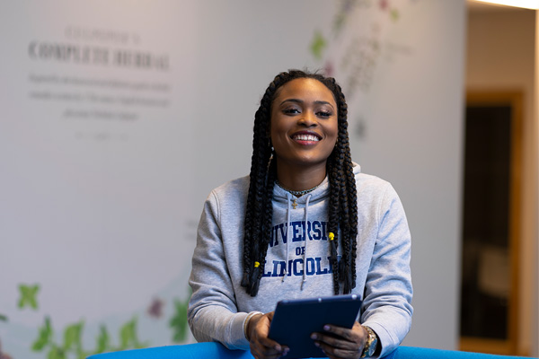 A student stood with an Ipad smiling