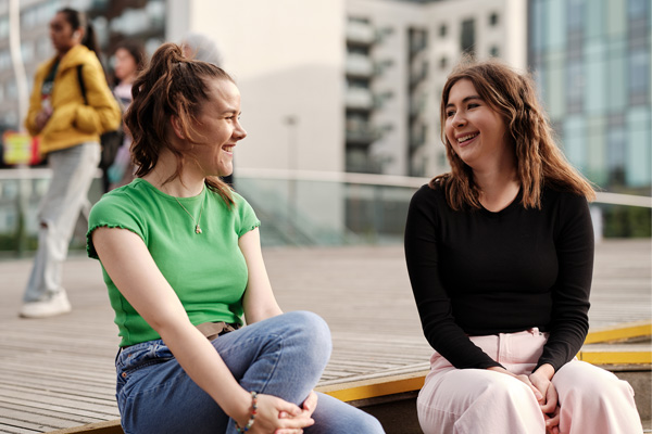 Two students sat talking and smiling